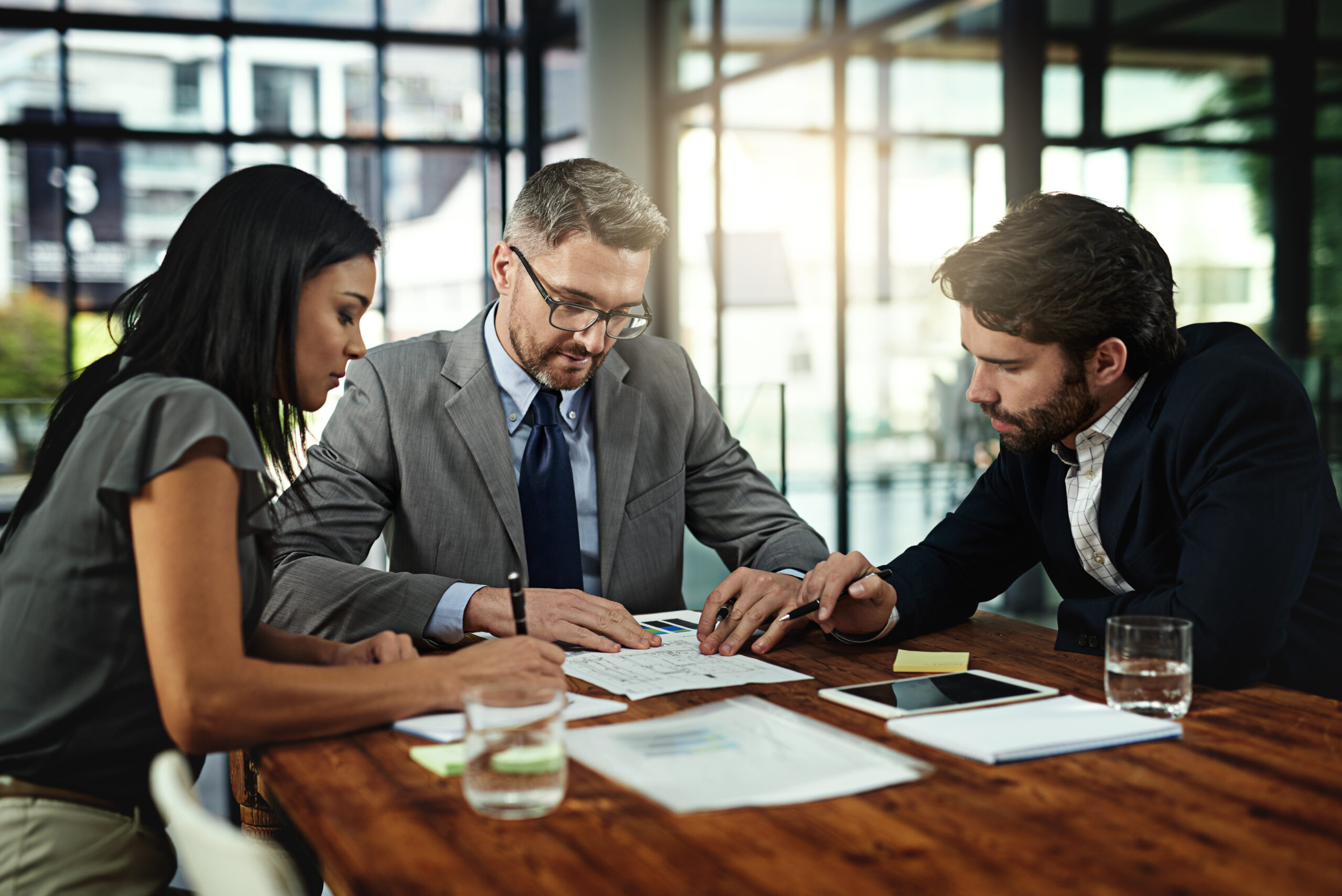 Businesspeople, deal and meeting with documents in boardroom, office and sign for corporate b2b sale. Collaboration, attorney with paperwork and contract, management and planning for negotiation